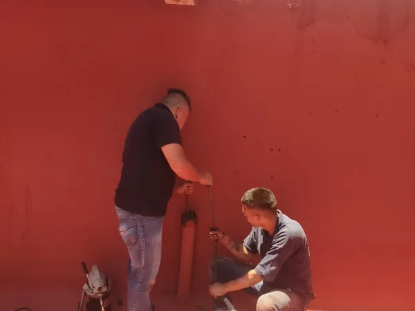 Dos plomeros de AFA desazolvando una bajada de agua con sonda en una azotea