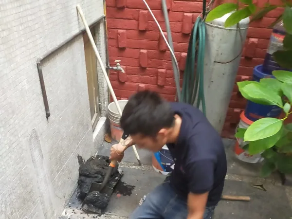 Plomero de AFA destapando un registro en el patio de una casa